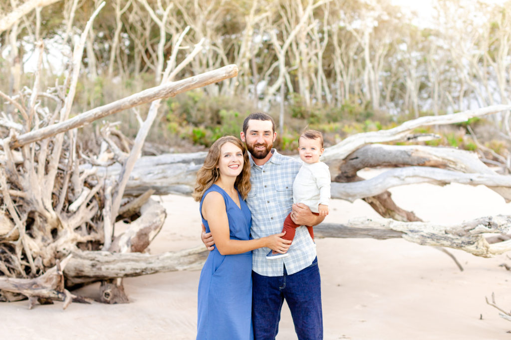 Family of three at Driftwood beach  for a family portrait session. Little boy smiling and having fun.
