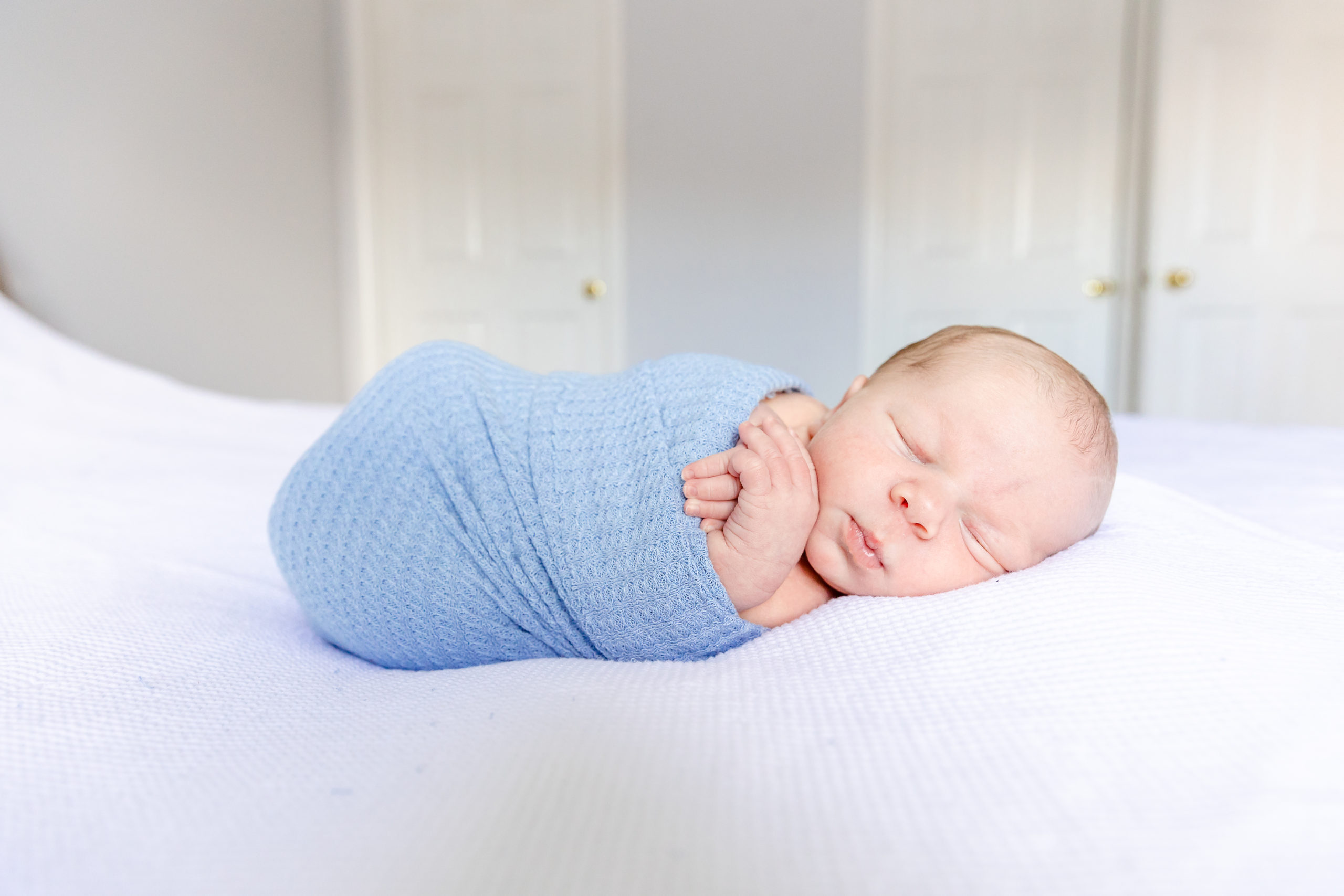 Lifestyle Newborn Session with a baby wrapped in blue blanket.