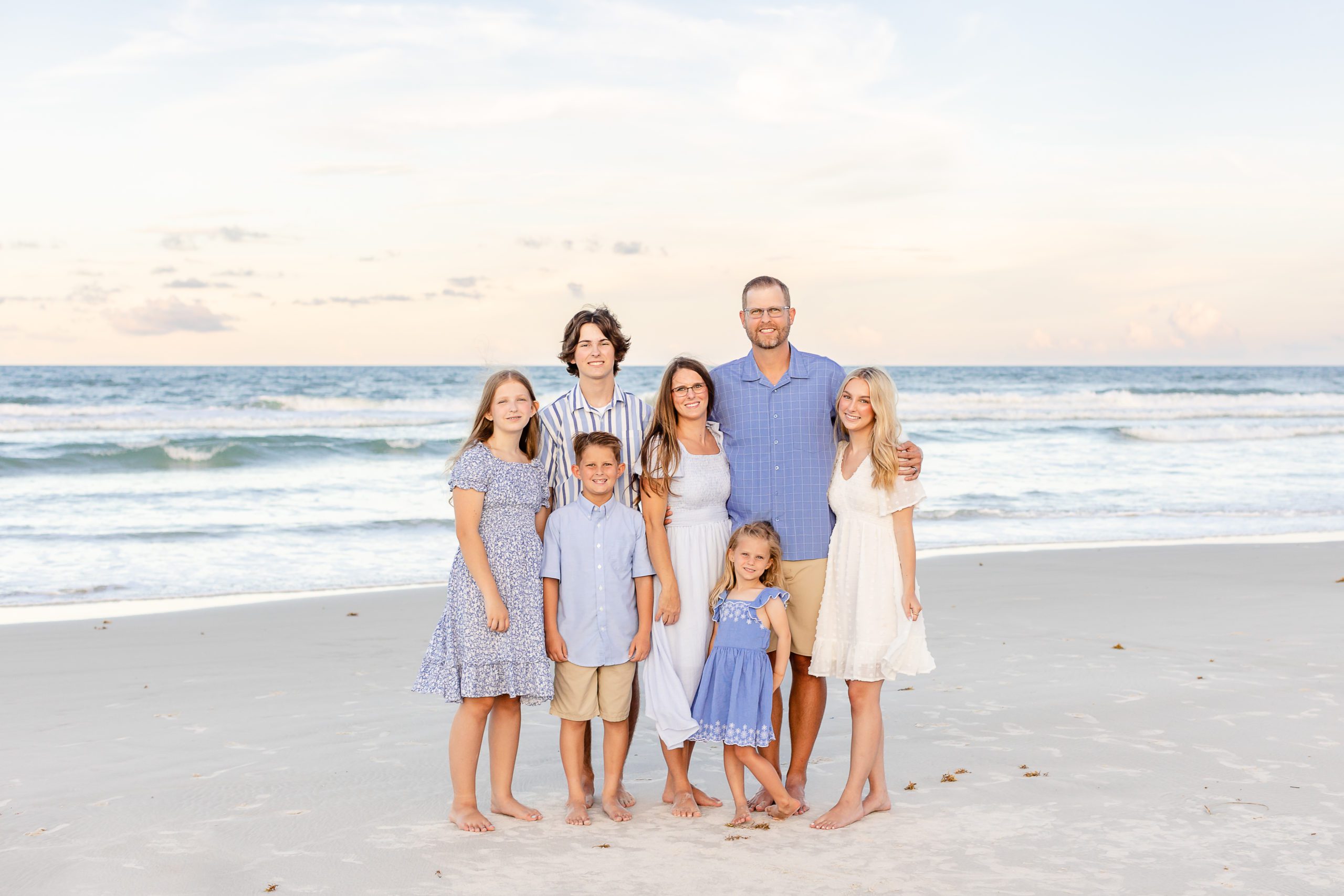 A family in Jacksonville Beach Fl at sunset posing for a family photo
